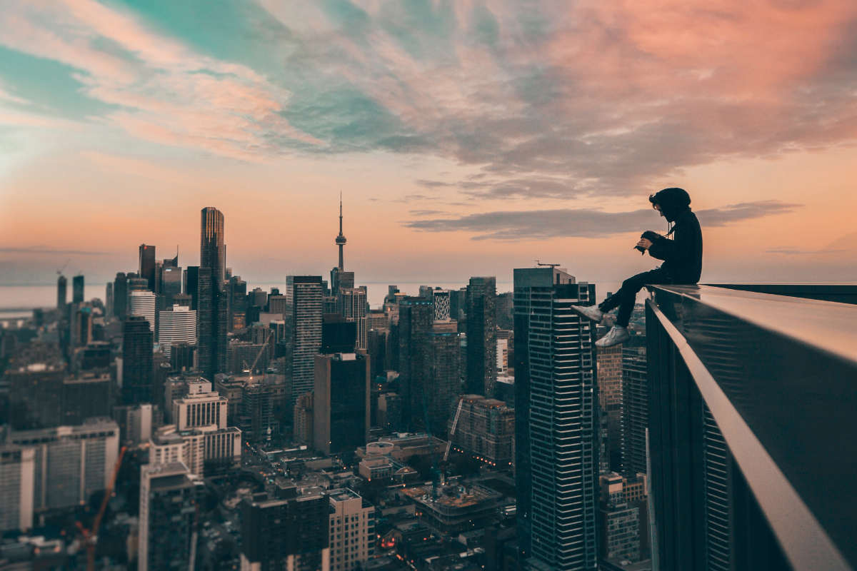 Young man sitting at the edge of a skyscraper