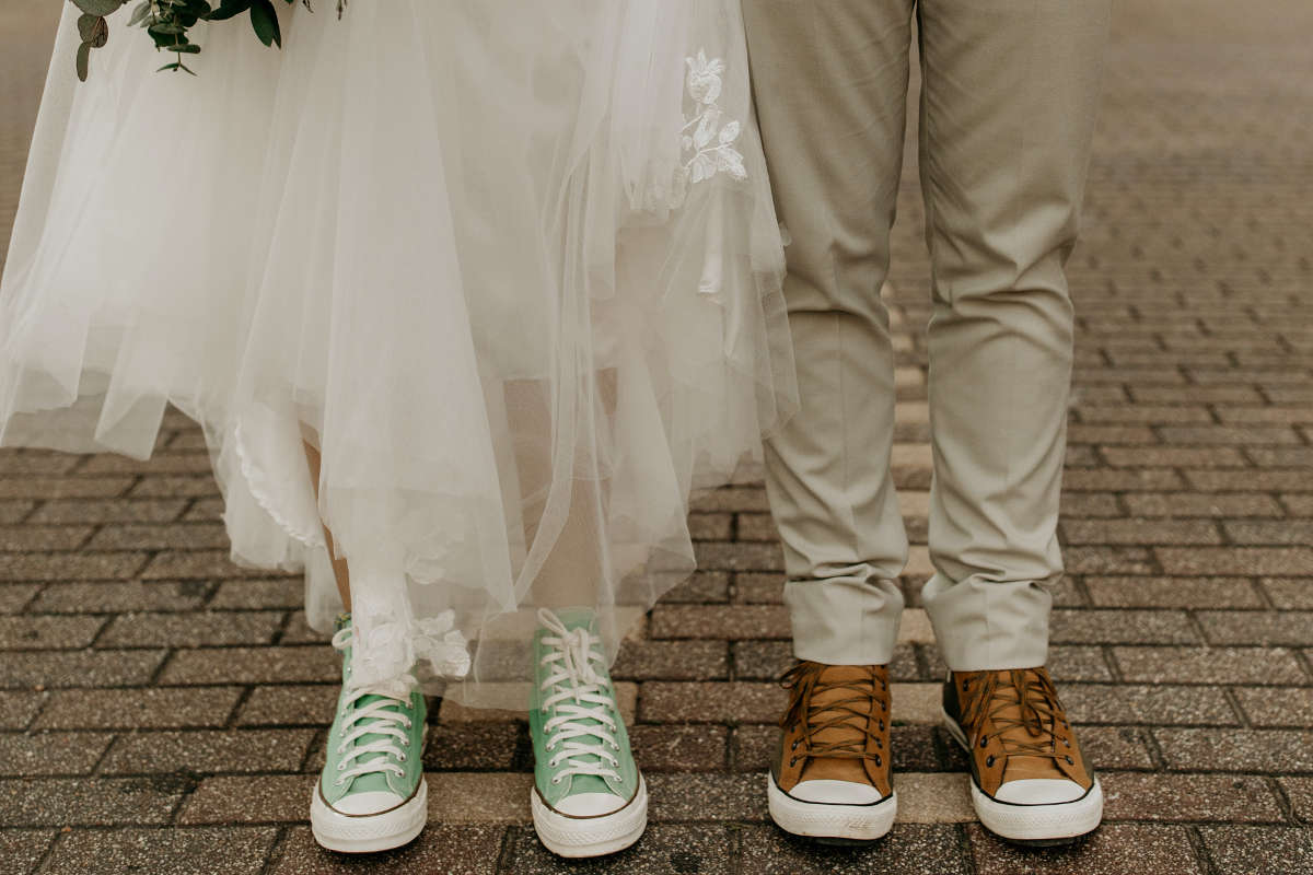 Close up on a bride and groom feet wearing Converse shoes