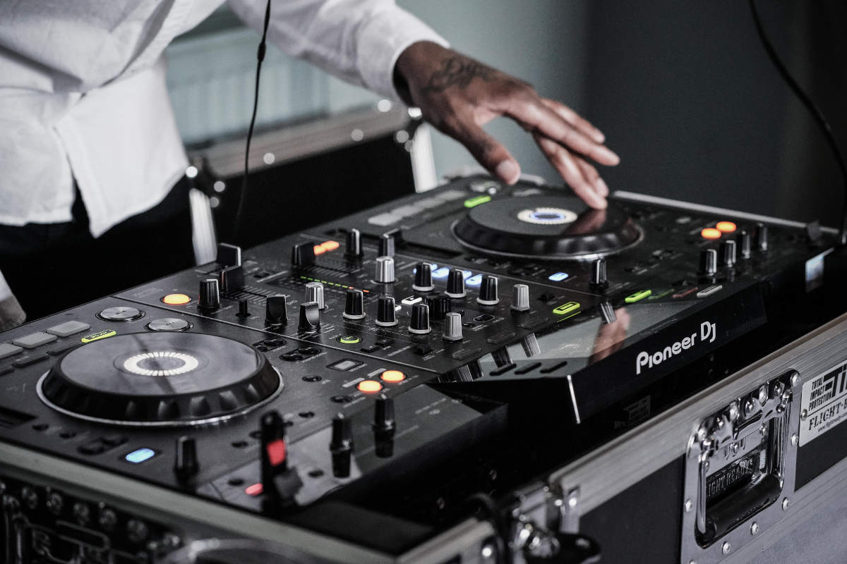 Turntable close up at an angle with a DJ wearing a white shirt running it
