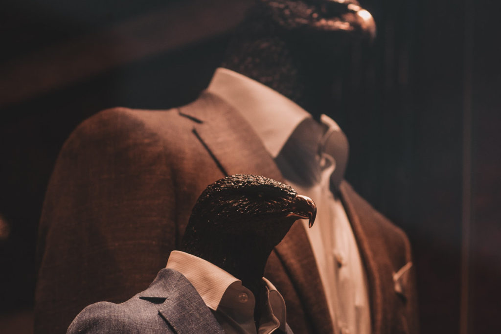 Mannequins with eagle heads wearing tailored suits on a shopping window